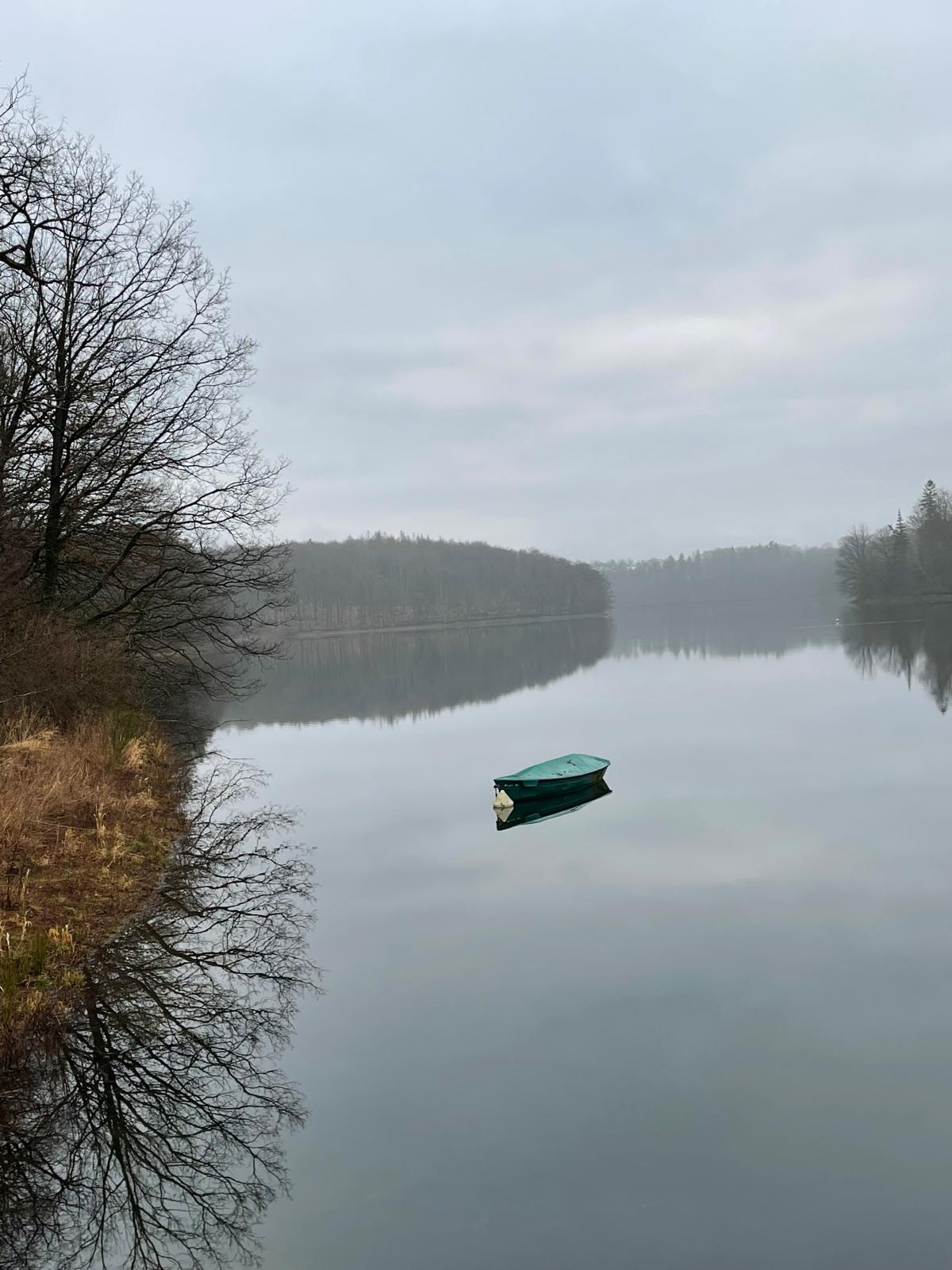 Ruderboot auf einer spiegelglatten Talsperre an einem nebligen Morgen