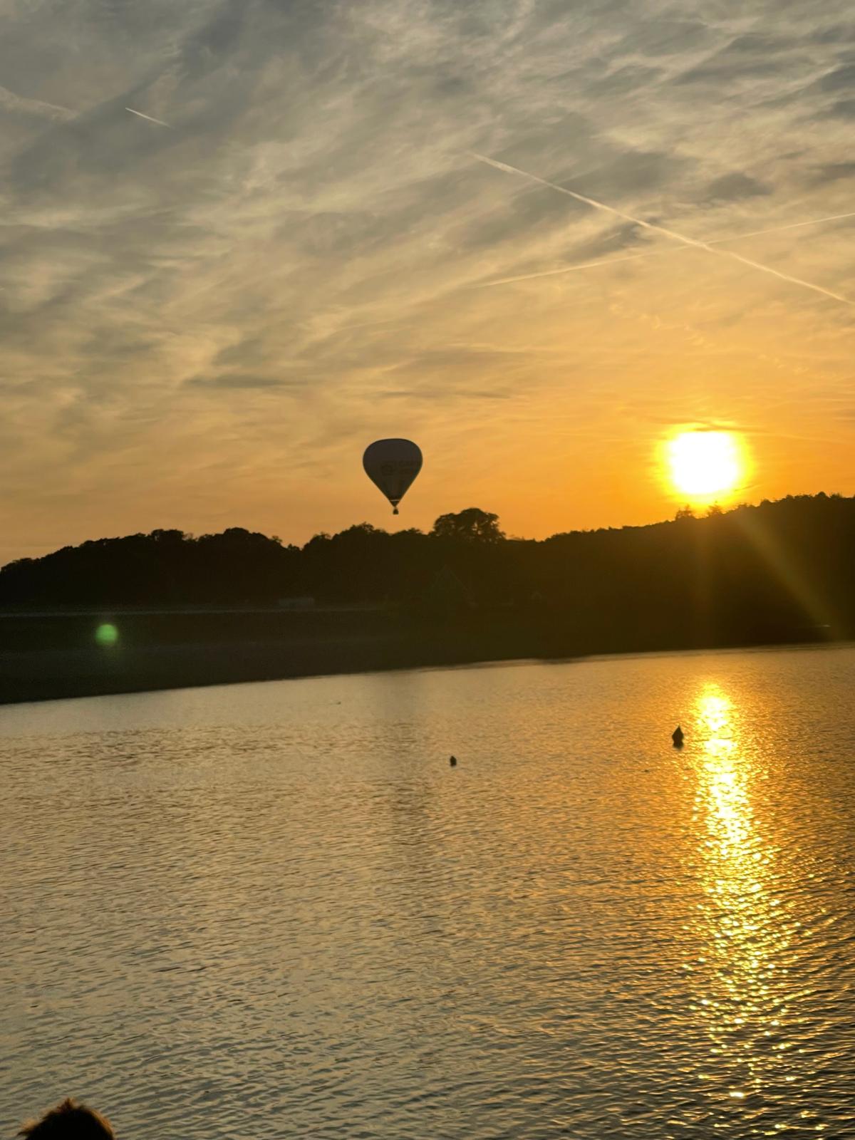 Heißluftballon über einer Talsperre bei Sonnenuntergang